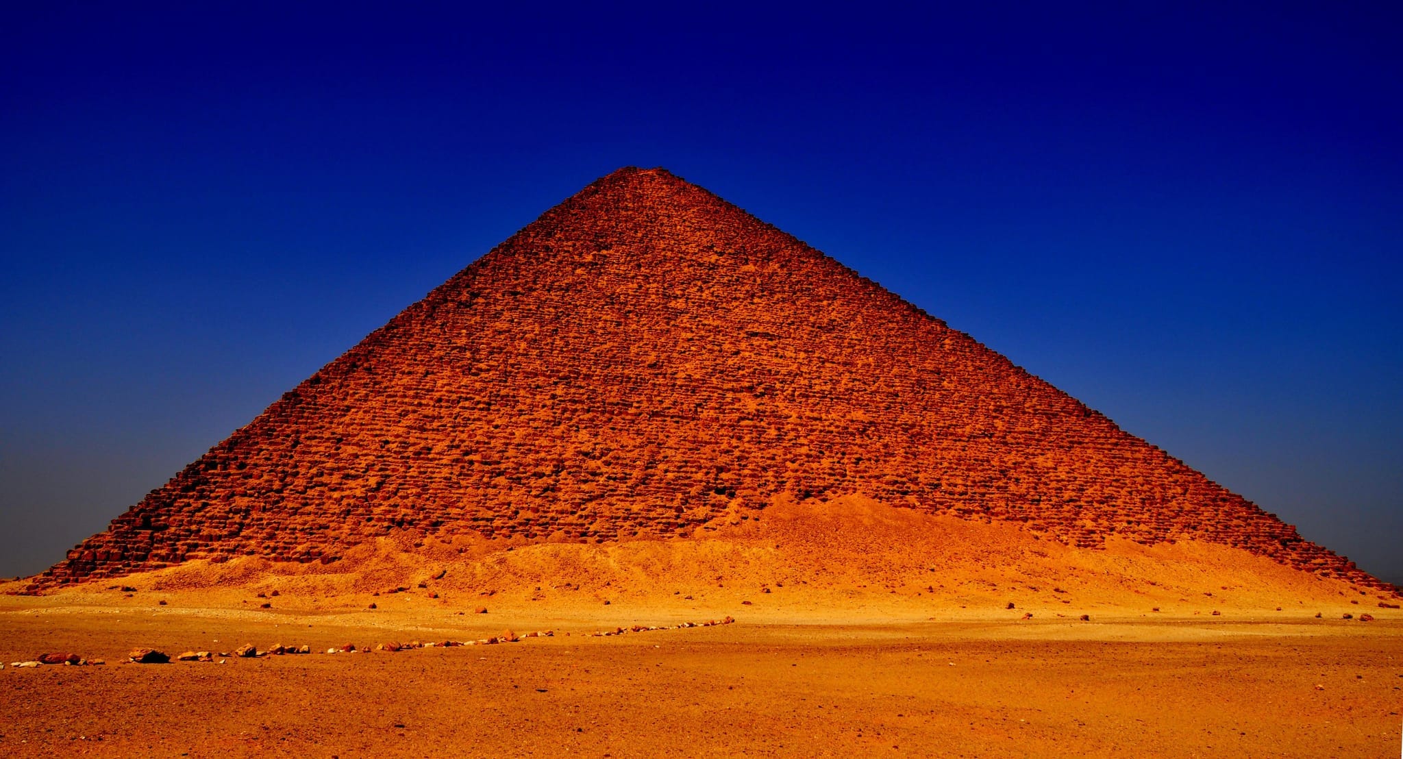 Die Rote Pyramide in Dahshur, Ägypten, unter einem klaren Himmel präsentiert, hebt ihre massive Kalksteinstruktur und historische Bedeutung als eine der frühesten glattseitigen Pyramiden Ägyptens hervor.