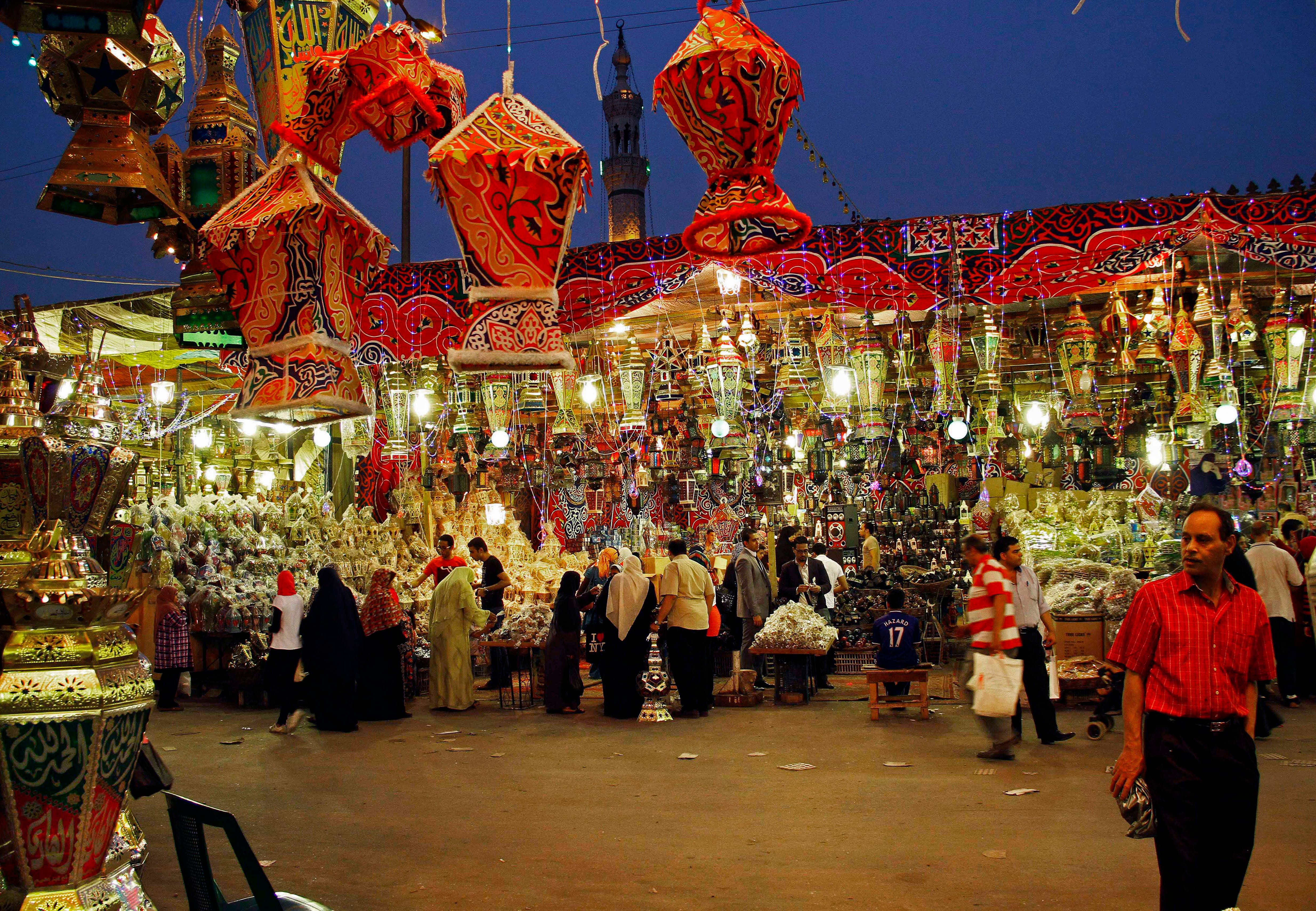 Colorful lanterns illuminate a street at night during an Egyptian festival, with people strolling below.