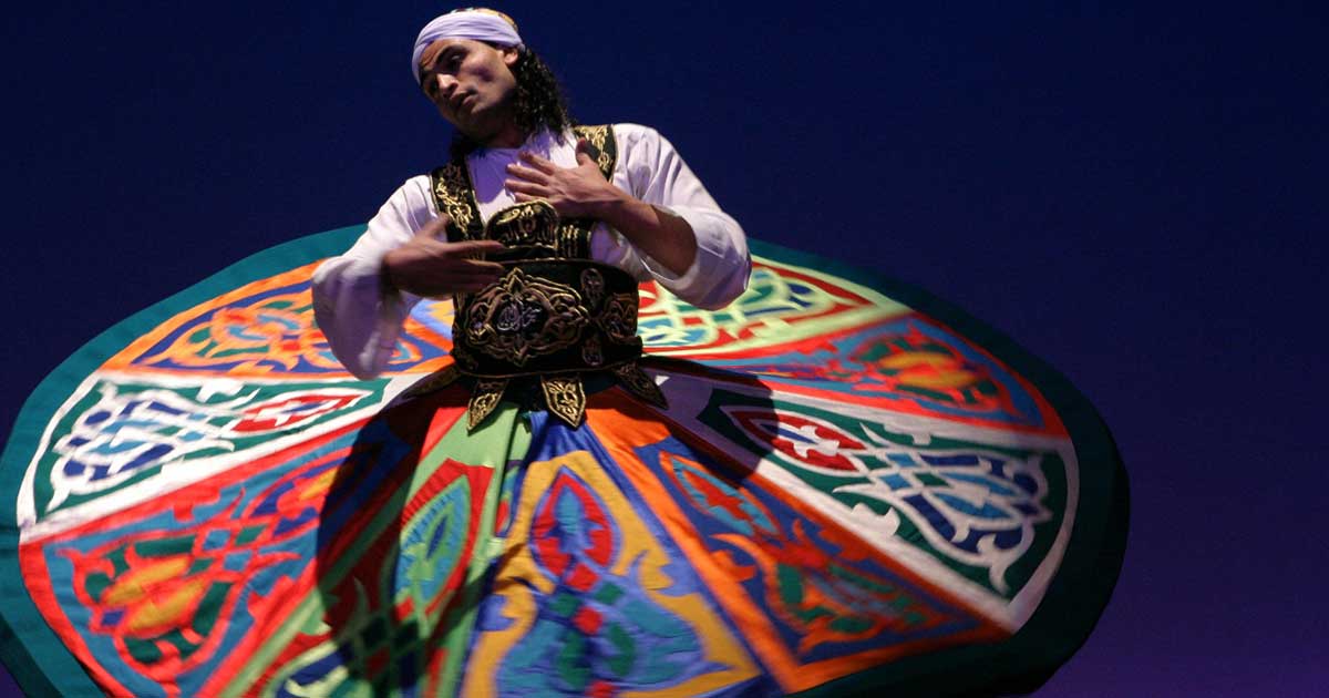 A Tanoura dancer in colorful traditional dress spinning gracefully during an event in Egypt.