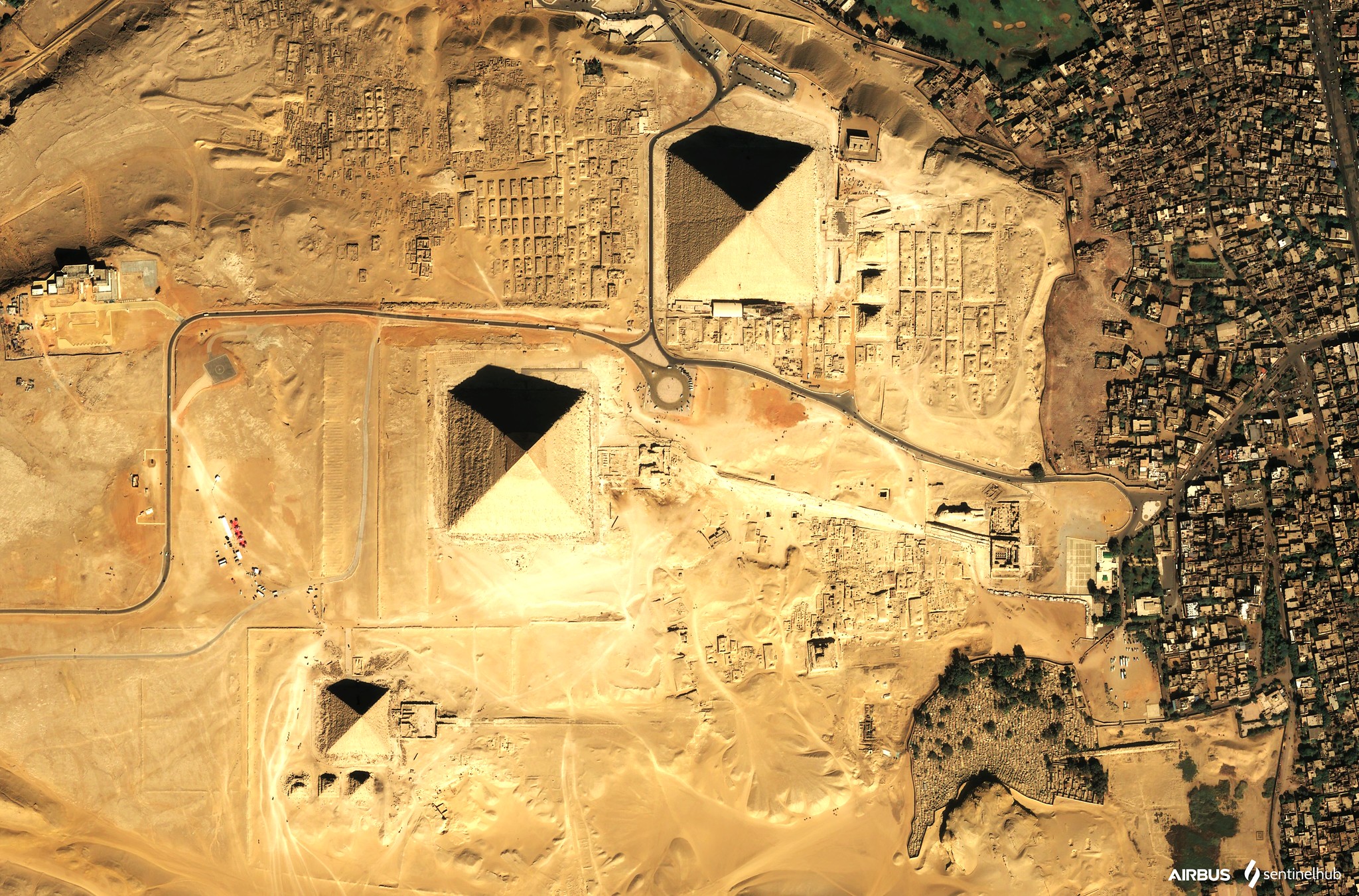 As icônicas Pirâmides de Gizé erguem-se majestosamente no vasto deserto arenoso sob um dramático céu nublado, simbolizando a antiga civilização egípcia e um destino de viagem de renome mundial.